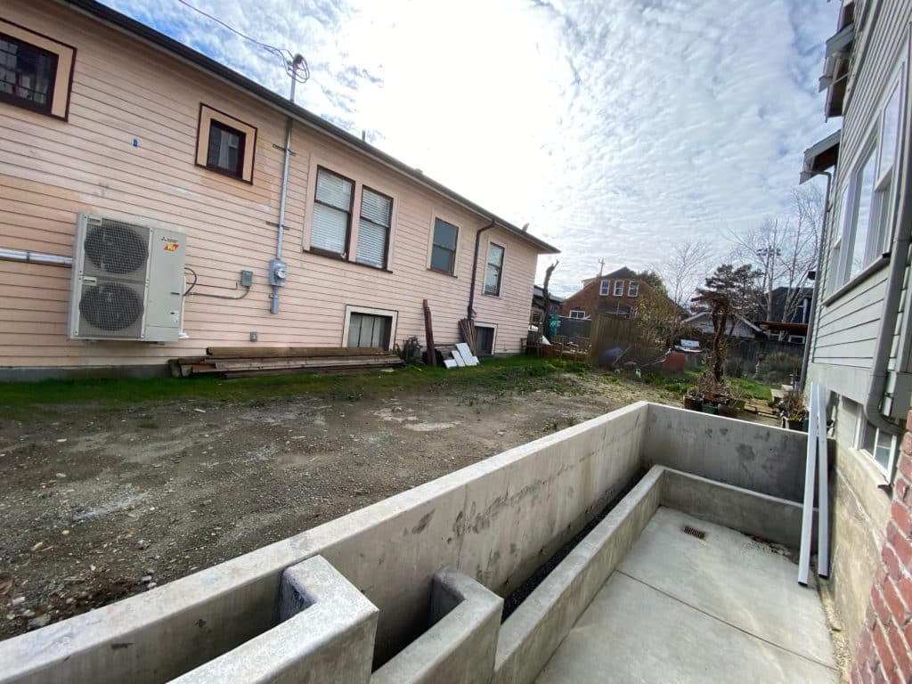 Photo of the yard during build, with the concrete retaining wall and planters poured.