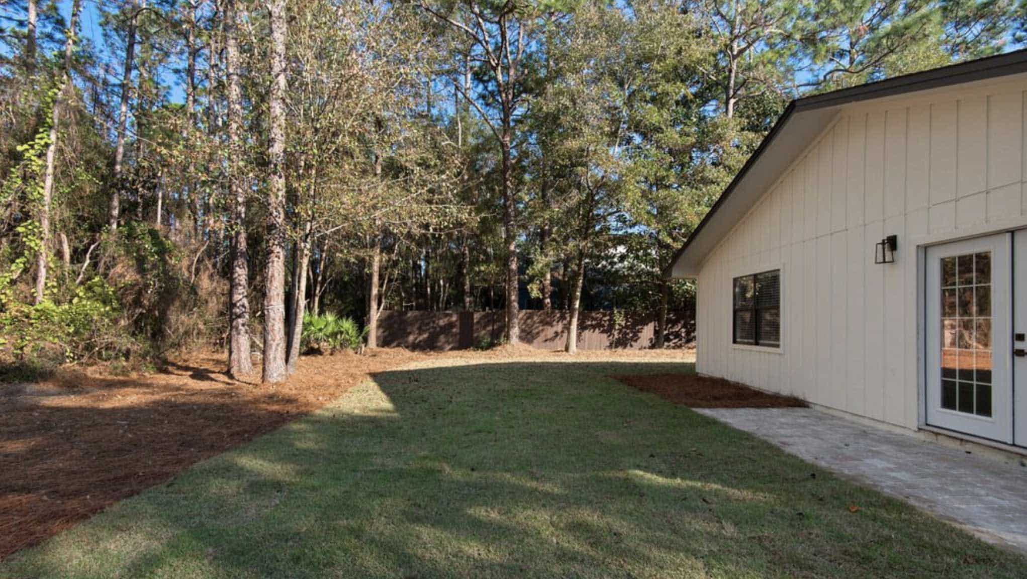 Before photo of backyard with large lawn and barren planting beds