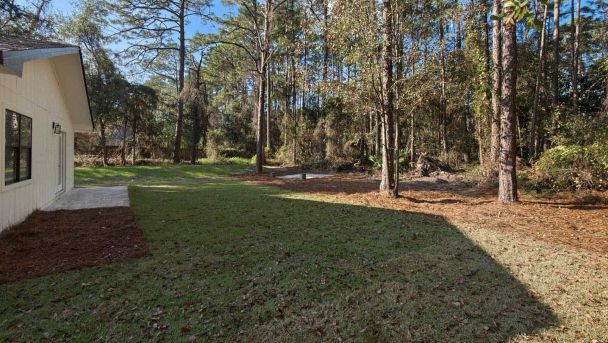 Side view of yard before new landscaping with no planting except a large bare lawn