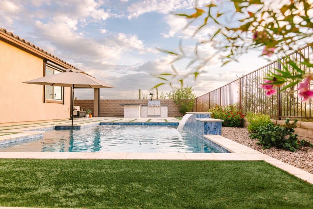 backyard with pool, artificial turf lawn, and colorful flowering plants