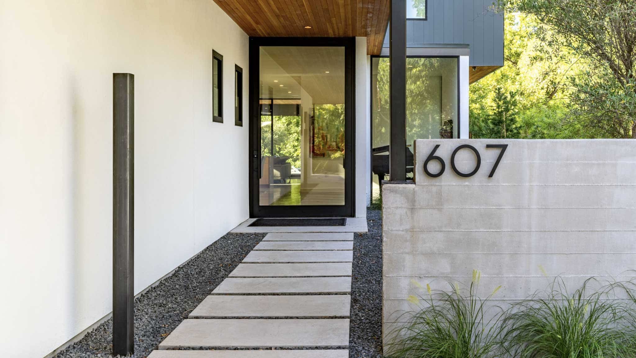 Front of modern home with huge glass front door and concrete paver front path