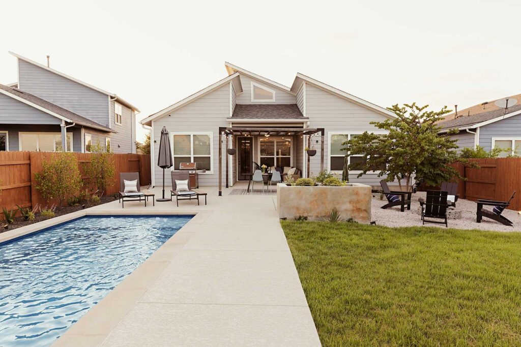 backyard with pool, lawn area for dogs, and gravel fire pit seating area