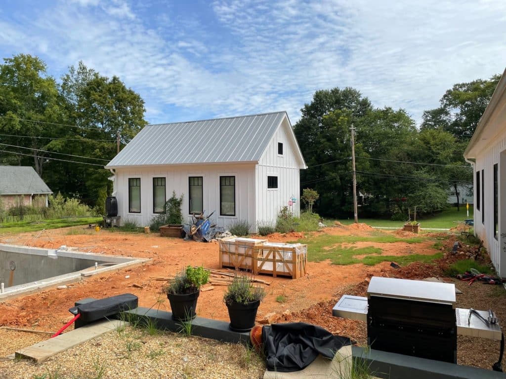 View of the empty backyard, including red clay dirt and the ADU before landscaping and hardscaping work. 