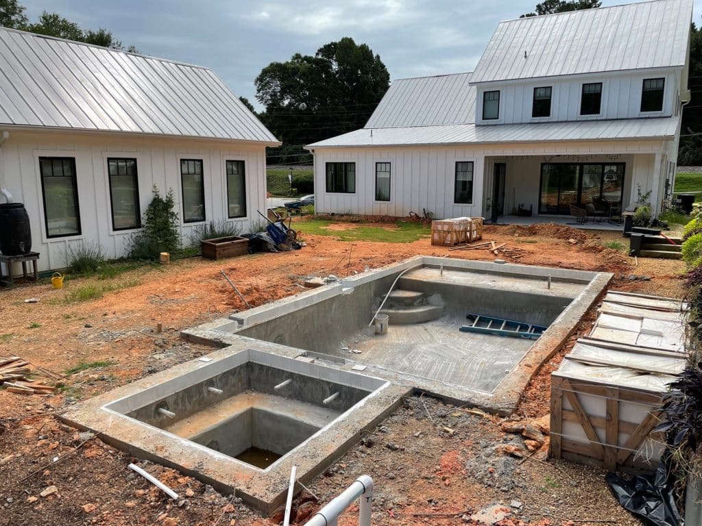 View of the empty backyard, including the hot tub and pool construction before landscaping and hardscaping work. 