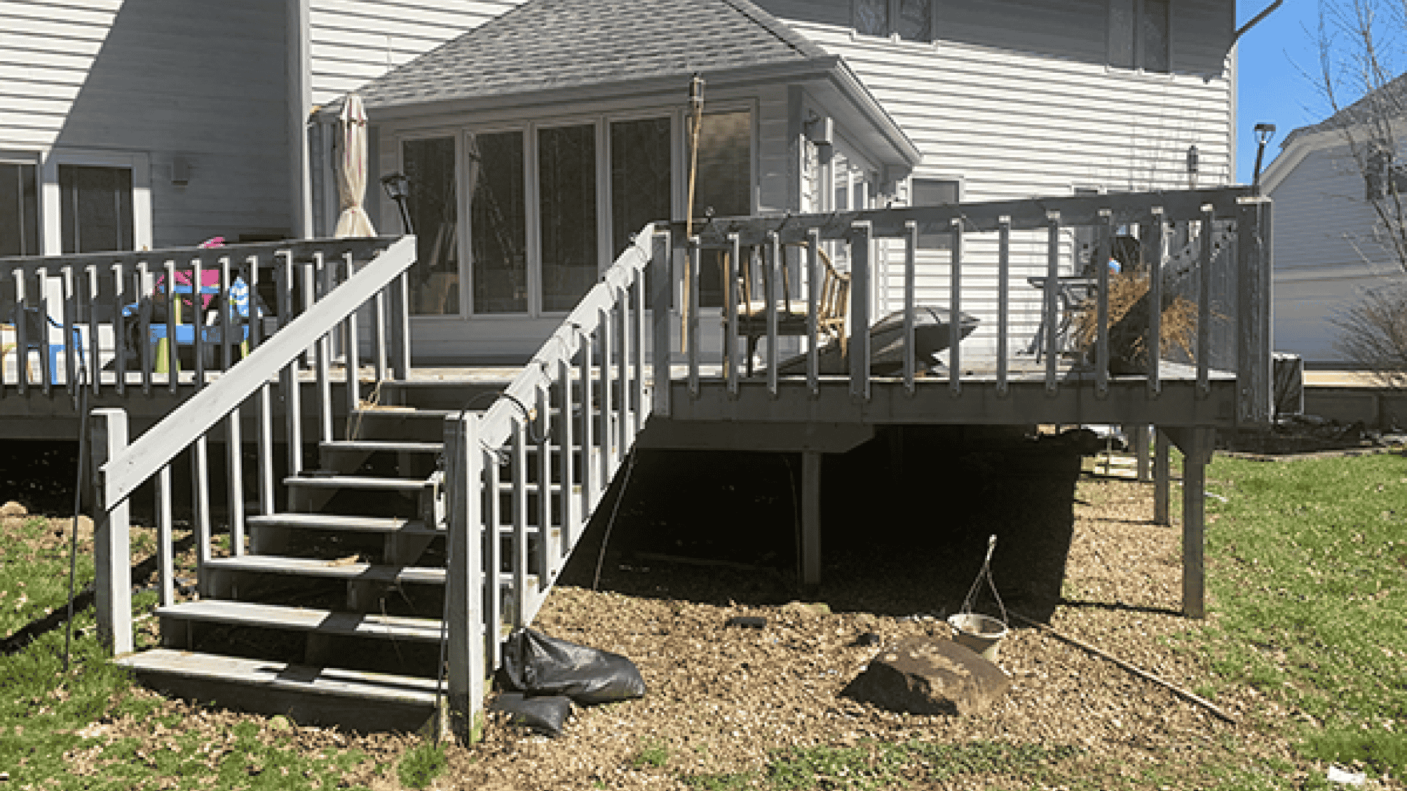 Before photo of yard with aging deck and patchy grass surrounding