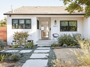 Bright white modern single story home with paver path and planting beds in front yard